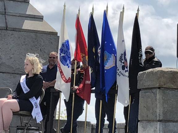 Veterans stand by flags during the ceremony. Seated is Danielle Penny, Miss Cumberland County Teen, who sang the National Anthem. She is a student at Newton High School.