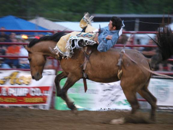 A cowboy tries to hang onto a bucking bronco.