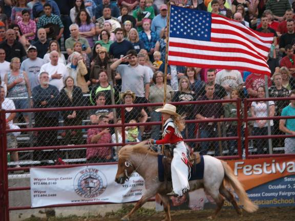 A little cowgirl gets the crowd in a patriotic mood riding with 'Old Glory'.
