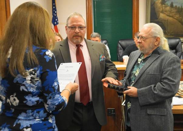 PHOTOS BY VERA OLINSKIFrom left, Borough Clerk Robin Hough gives the Oath of Office to Mayor George Hutnick, while his father, George Hutnick, holds the Bible.