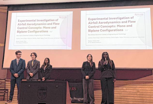 Samuel Tobachnick stands on stage with other students.