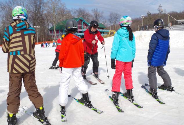 Ski instructor David Woods of Montclair teaches the youngsters how to snowplow down the slope Sunday afternoon at the National Winter Activity Center.