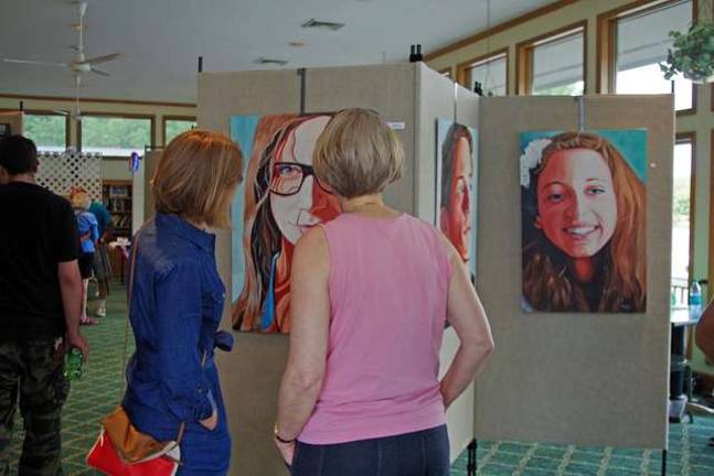 Two ladies stop to admire paintings by Highland Lakes artist and Vernon Township High School art teacher Doug Miller.