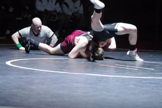 A wrestling referee watches the action on the mat.