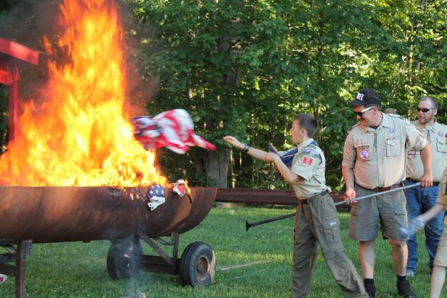 Boy Scout Scott McCarrick retires a flag by tossing it onto the flames.