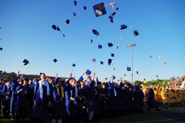 The graduating class toss their caps to the sky.