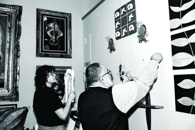 Ceramic artist Agatha Wyman joins Silken Wool Home owner Behrooz Ghorbanian to hang her artwork at his store in Hamburg, N.J.