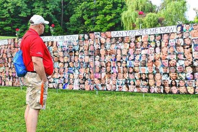 A man looks at posters with faces of people who have died from addiction at the 10th annual Changing the Face of Addiction Recovery Walk.