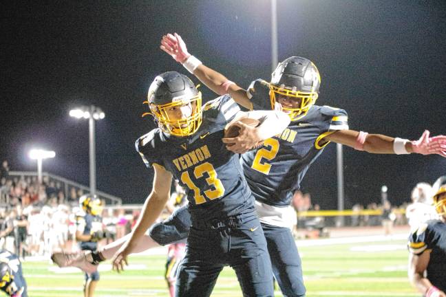 <b>In the third quarter, Vernon quarterback Nathaniel Kimkowski (13) celebrates a touchdown with teammate Sam Simone. Kimkowski made three touchdowns in the game.</b>