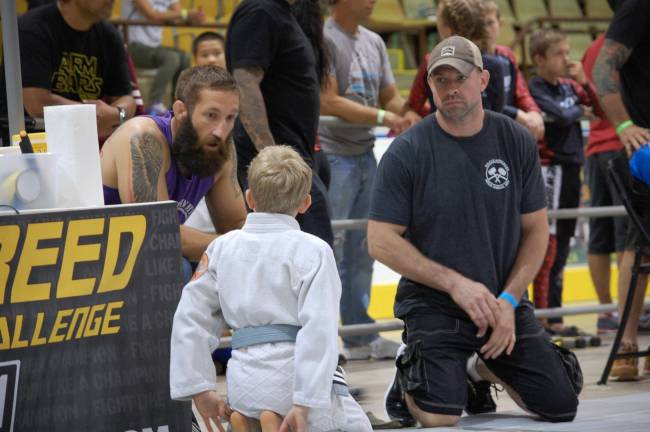 Coaches Frank Wallace (left) and Moe Johnson (right) speak with Josh Enberg before his match
