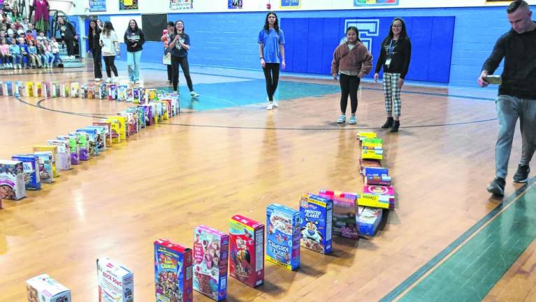 A student and a staff member recognized for their acts of kindness start the cereal boxes falling in succession. (Photo by Kathy Shwiff)