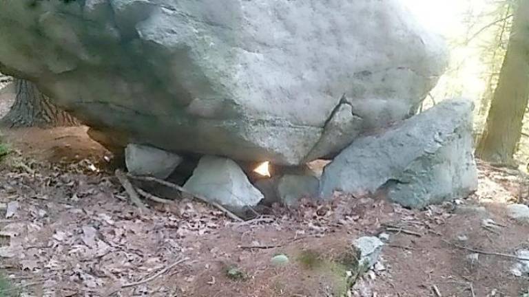 Light shines underneath a propped stone. As Kreisberg observed, “The beams projected beneath the boulder form a nearly perfect equilateral triangle shape of light at sunset, on the day of the Summer Solstice only. The triangle light form is seen at the base of the boulder when viewed from the east side and is projected with one point up and two points down.”