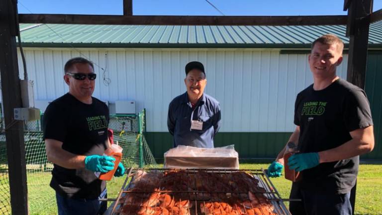 Art Fetzer and his sons sprinkle secret spices on barbecue chicken at the Sussex County Board of Agriculture pavilion at the fairgrounds. (Photo provided)