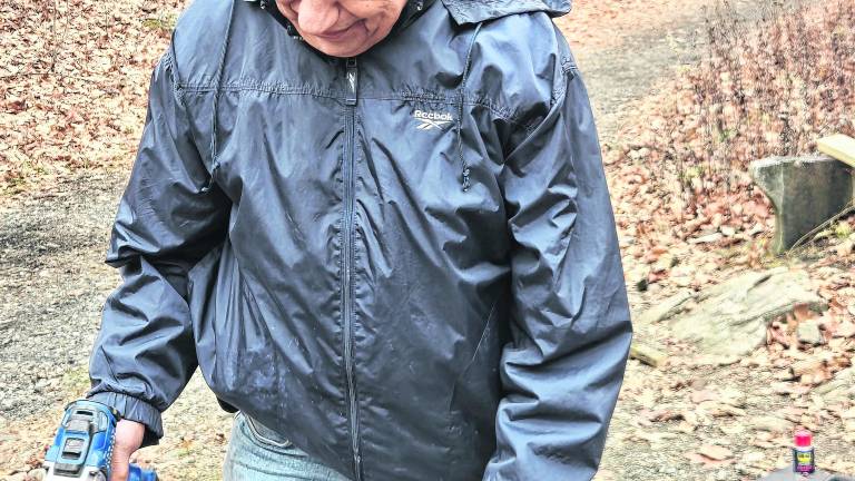 <b>Martin Grossman, president of the Paulinskill Valley Trail Committee, using old wood as a template before drilling into replacement pieces as part of ongoing trail maintenance. </b>